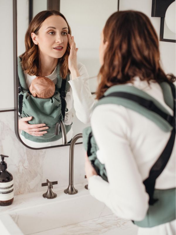 Madre sosteniendo con ternura a su reci&eacute;n nacido con la mochila E-Carrier Diamond Green de Quokkababy y los tirantes cruzados